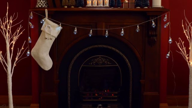 Nightime osy Christmas holiday decorated mantelpiece and fire place in red and white theme, adding Santa Sack full of gfts.