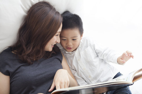 A mother reading a picture book with her son happily