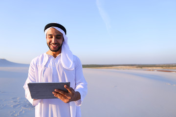 Successful Arabian businessman holds in hands and uses tablet, s