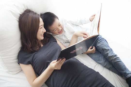 Parents reading funny picture books on bed