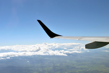Airplane wing during flight against blue sky with clouds seen from high angle