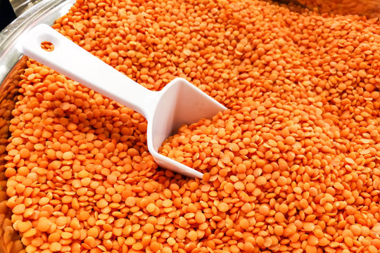 Heap of organic red dal with ladle in bucket