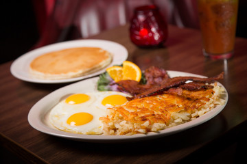 Grand slam breakfast of sunny side up eggs with hash browns and bacon