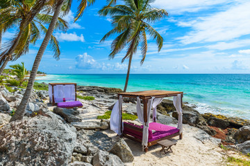 Beach beds under the palm trees on paradise beach at tropical Resort. Riviera Maya - Caribbean coast at Tulum in Quintana Roo, Mexico