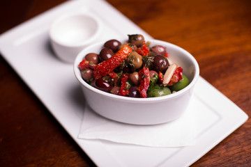 Overhead close up on tapas olives and picked peppers on white dish