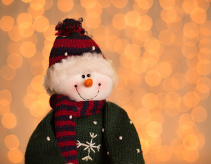 Toy Snowman against Christmas lights