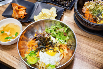 Bowl of hot Bibimbap on wooden table. Korean dish