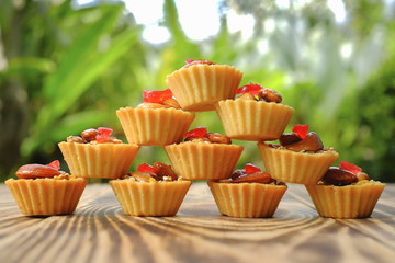 Almond nuts, pistachio, walnut , hazelnuts tart cake on  beautiful texture   of pine  wood  with green background