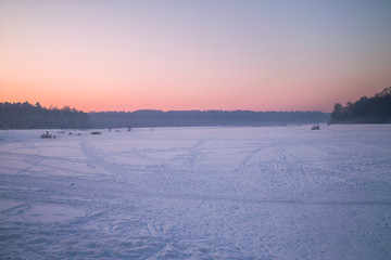 Winter sunset on the frozen lake in park