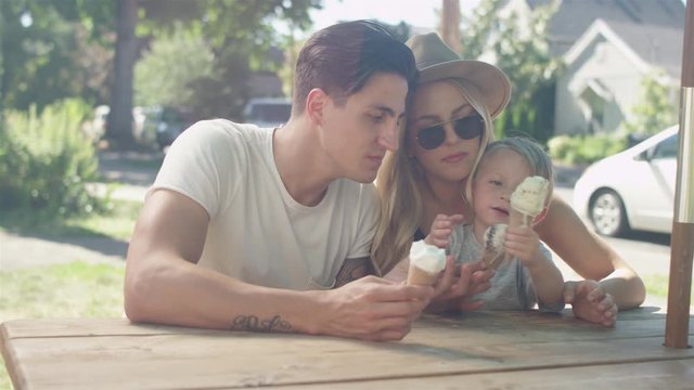 Young loving family eating ice cream cones at the park
