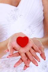 Female hands of bride with heart shaped red box