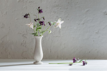 flowers in vase on background old white wall