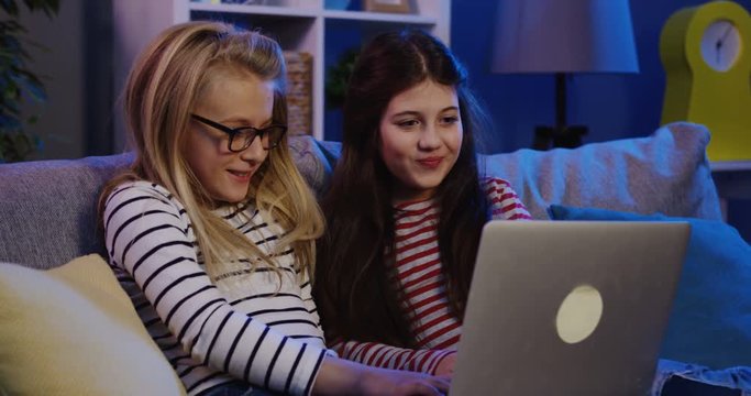 Two friends of teen girls watching something funny and than scarry on the laptop computer. Different emotions. Indoors
