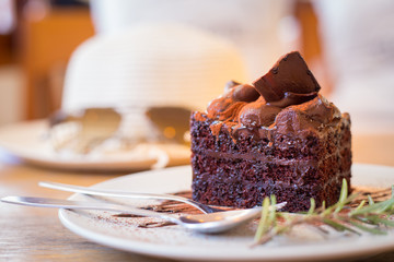 Chocolate cake on white plate with spoon.