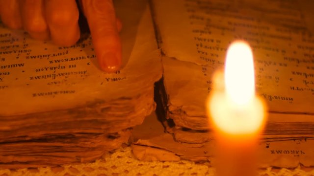 Elderly woman reading old book by candlelight

