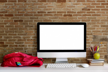 Fototapeta premium Workspace desk with desktop computer, red backpack, office supplies and books on table. Blank screen for graphic display montage. Mock up workplace.
