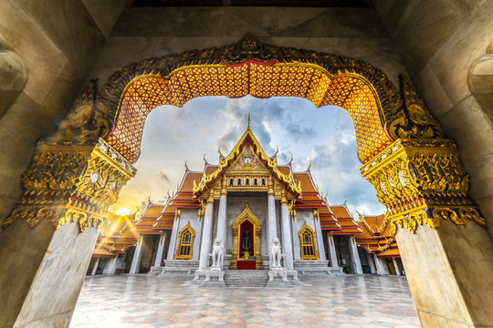 The arch at the Marble Temple, Wat benchamabophit, Bangkok, Thailand. Sunrise at the roof creating sun star and lens flare effect .