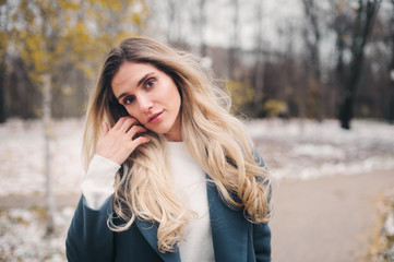 Naklejka premium winter portrait of young woman walking in snowy city park in warm grey coat