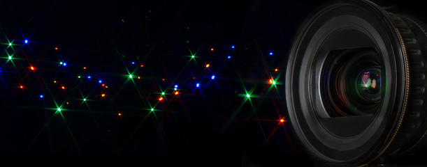 Fototapeta na wymiar Photo lens with glittering stars flash over black background