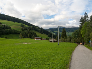 Asphalt road from low point in Alps mountains at hills and mountain village background. Road trip concept, Italy, autumn 2017