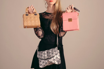 Young woman posing in black dress and three hand bag