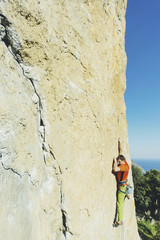 A man rock climbing on rocks against the background of the sea.