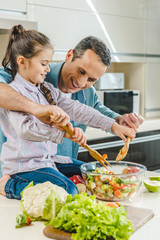 father with daughter mixing salad in bowl