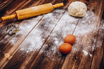 Place on the wooden table with rolling pin, dough, eggs and flour for cooking Christmas pastry