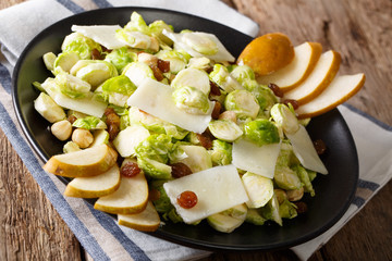 salad from Brussels sprouts with nuts, cheese, raisins and fresh pears closeup. horizontal