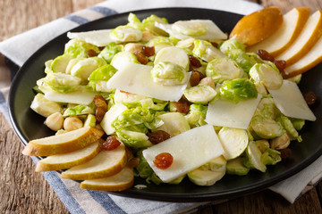 Organic salad from Brussels sprouts with hazelnuts, cheese, raisins and pears. horizontal