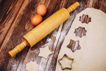 Place on the wooden table with rolling pin, dough, eggs and flour for cooking Christmas pastry