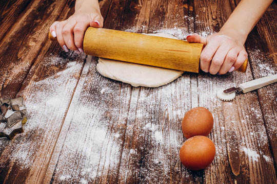 Woman makes Christmas pastry on the dough on wooden table