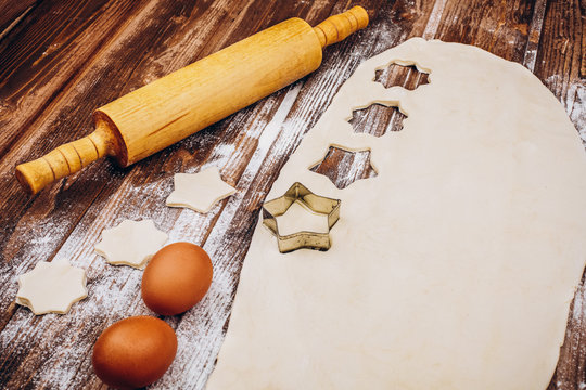 Place on the wooden table with rolling pin, dough, eggs and flour for cooking Christmas pastry
