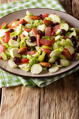 Fresh salad from Brussels sprouts, dried cranberries, almonds and ham close-up on a table. vertical