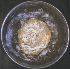 Making homemade bread from scratch. The raw dough is in the form of a ball and sprinkled with flour. 