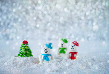 Three sugar candy bears in the snow on bokeh background with copy space for season greeting Merry Christmas or Happy New Year. Selective focus