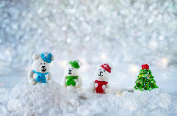 Three sugar candy bears in the snow on bokeh background with copy space for season greeting Merry Christmas or Happy New Year. Selective focus