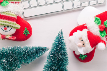 Wooden working table with computer keyboard, mouse , christmas socks and tree. View from above with copy space.