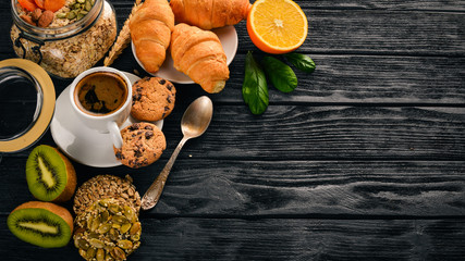 A healthy breakfast. Orange juice, kiwi, croissants, cookies, coffee, on a wooden surface. Top view. Free space for text.