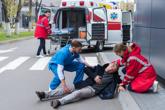 doctors helping injured man lying on a street