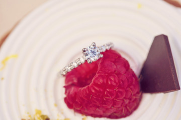Engagement set of rings on the top of the sweet raspberry cake