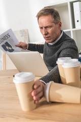 tired middle aged man taking one more coffee in paper cup