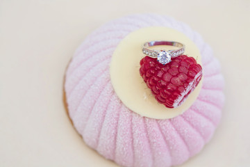 Engagement set of rings on the top of the sweet raspberry cake