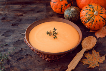 Pumpkin puree soup with thyme on a dark wooden background.