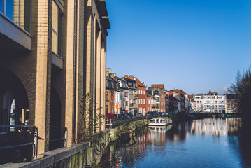January, 2th, 2017 - Ghent, East Flanders, Belgium. Portus Ganda marina with colorful belgian street, town houses and barges in docks reflected on the water of canal in flemish city Gent by sunny day.