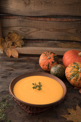 Pumpkin puree soup with thyme on a dark wooden background.