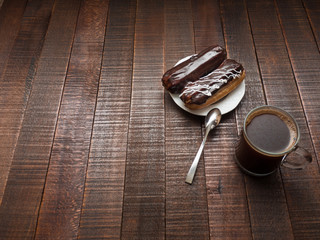 Coffee and eclairs for breakfast on a wooden table.