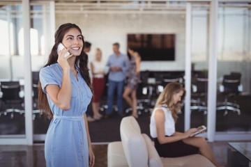 Obraz premium Young businesswoman talking on mobile phone at creative office