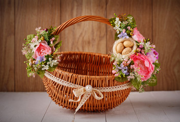 Fototapeta na wymiar Designer basket is decorated with flowers. Wicker basket for celebrating Easter and other holidays.