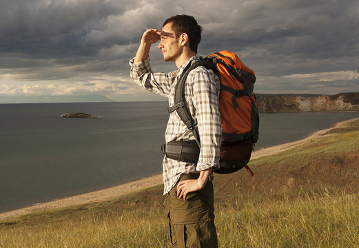 young tourist man with a backpack on the lake, Lake Baikal,  summer tourist walk, freedom and happiness
